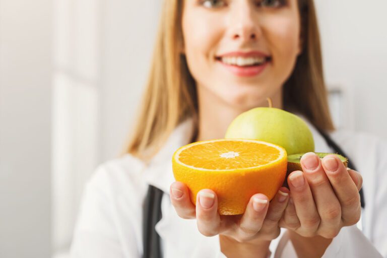 Smiling nutritionist woman with orange and apple at office, copy space. Healthy eating, right nutrition and slimming concept